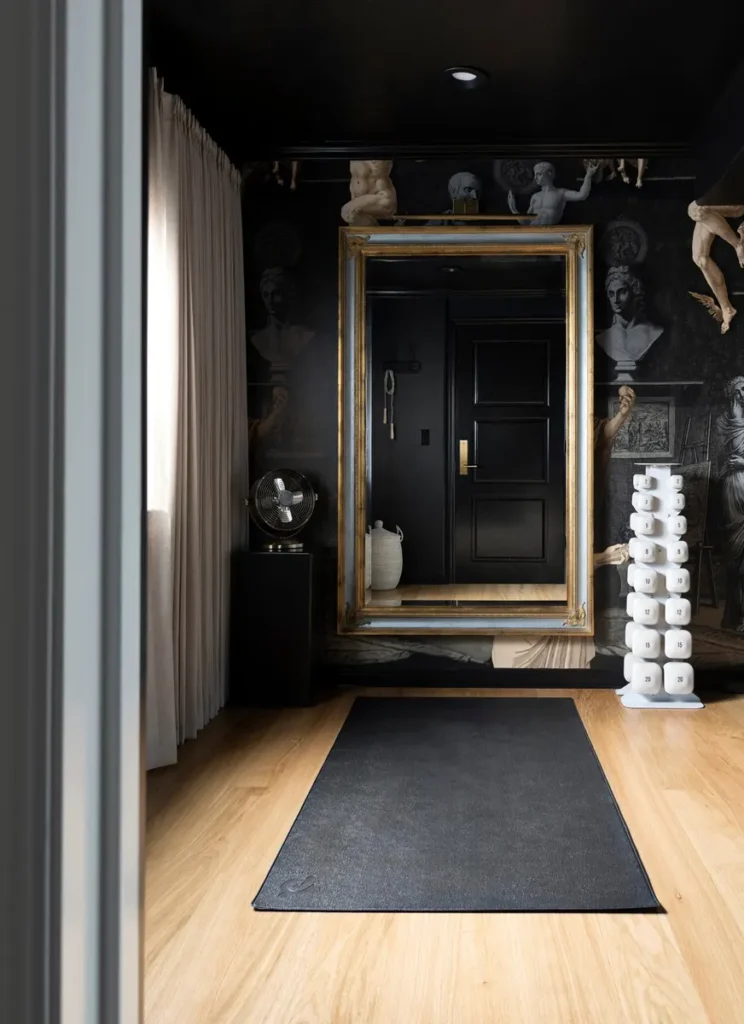 Small basement home gym with dark wallpaper and a gilded mirror, from Room for Tuesday