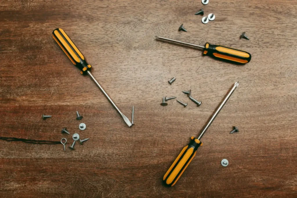 Screwdrivers and loose screws on a wooden surface