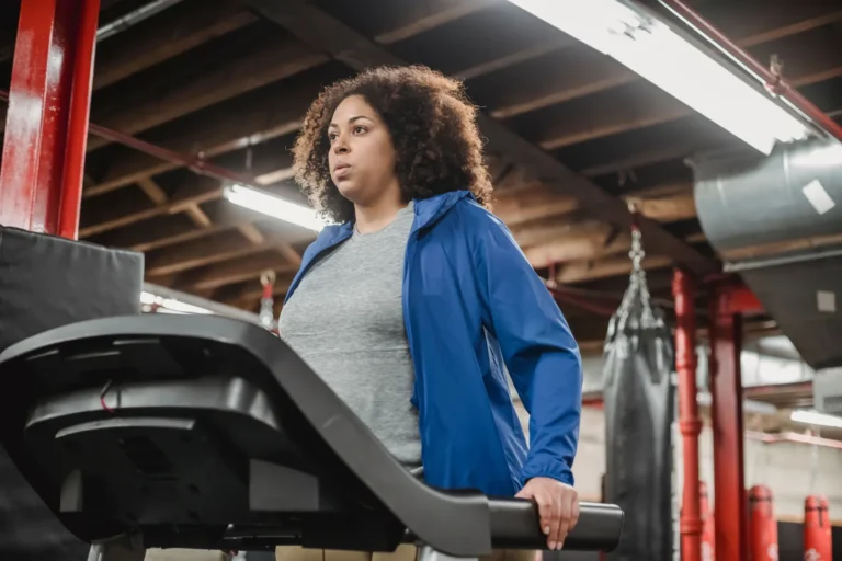 Woman in a blue jacket on a treadmill in a gym